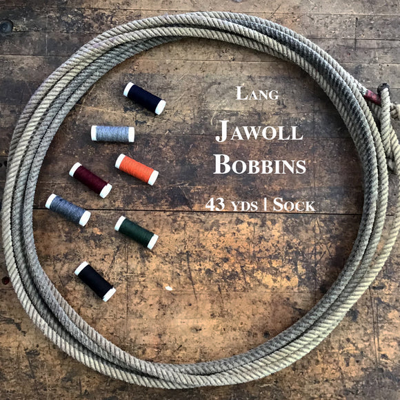 Seven Lang Jawoll Bobbins of various colors inside a lasso on a wooden table