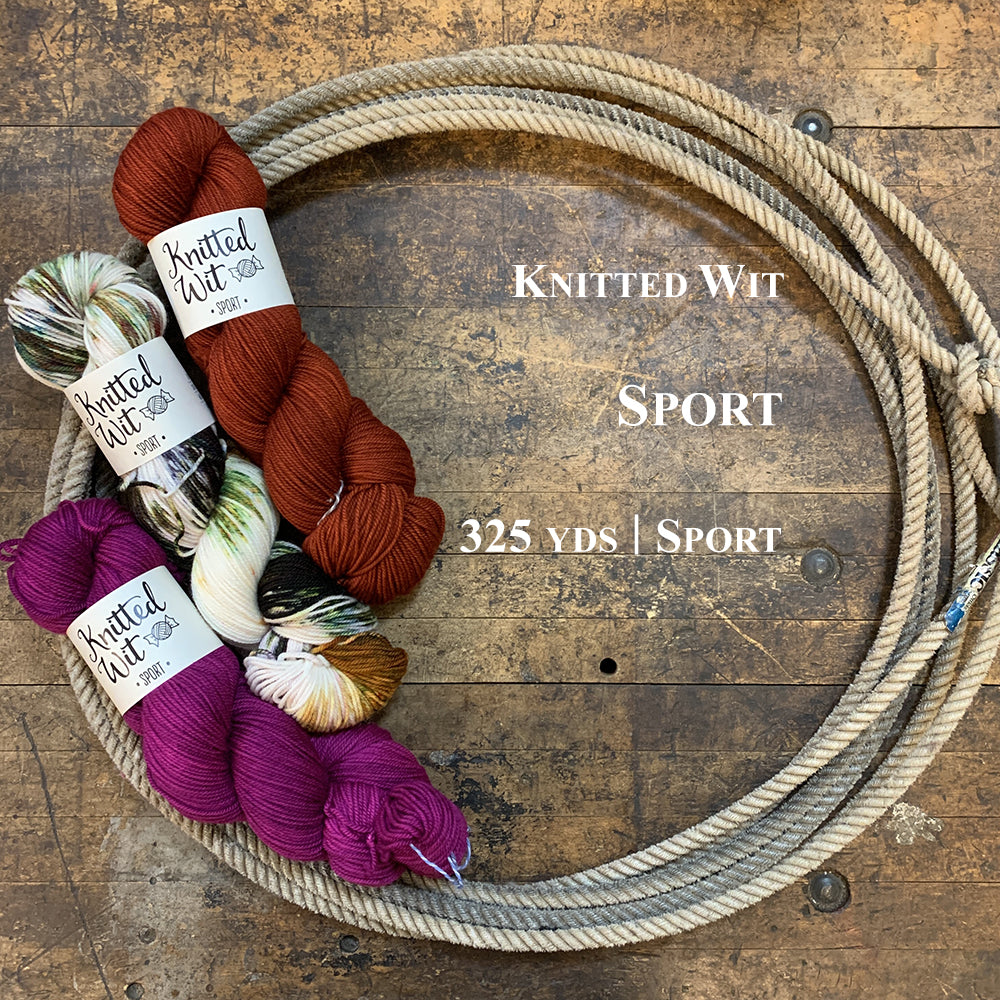 A photo of three hanks of Knitted Wit Sport yarn in a lasso on a wooden surface