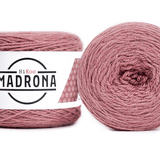 A photo of two light pink cakes of HiKoo Madrona yarn
