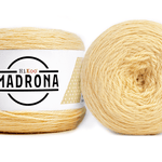 A photo of two light yellow cakes of HiKoo Madrona yarn
