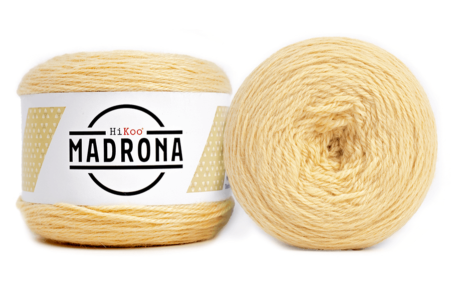 A photo of two light yellow cakes of HiKoo Madrona yarn