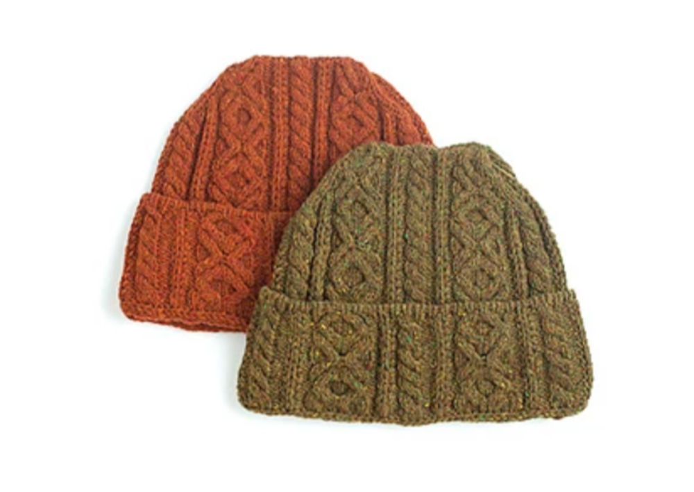 Two knitted, cabled hats on a white background