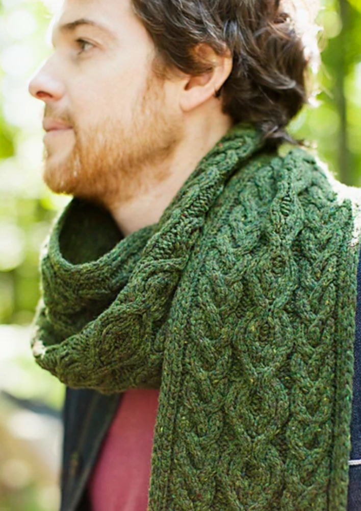 A man wearing a knitted, cabled scarf