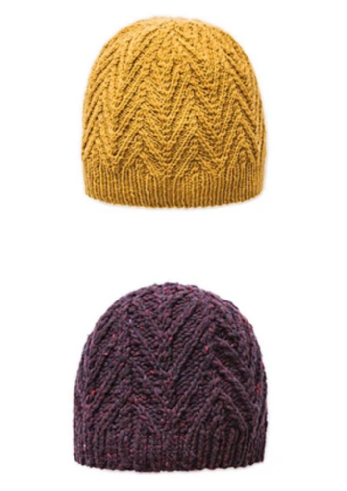 Two knitted, cabled hats on a white background