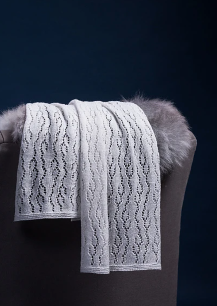 A white, knitted shawl thrown over a chair back