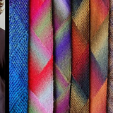 A woman wearing a multicolored scarf alongside other colorful scarves