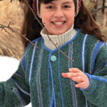 A young girl wearing a knitted jacket