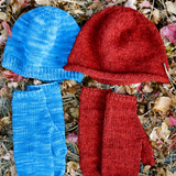 Two knitted hats and mittens on the grass