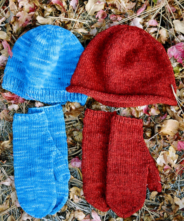 Two knitted hats and mittens on the grass