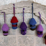 A variety of felted, birdhouse ornaments hanging on a wall
