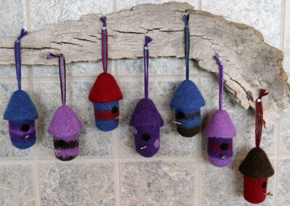 A variety of felted, birdhouse ornaments hanging on a wall