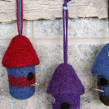 A variety of felted, birdhouse ornaments hanging on a wall