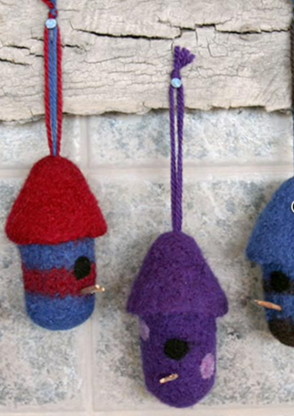 A variety of felted, birdhouse ornaments hanging on a wall