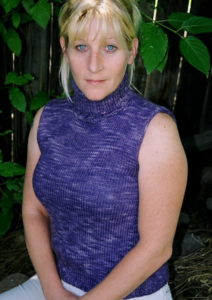 A woman wearing a sleeveless, knitted, turtleneck sweater