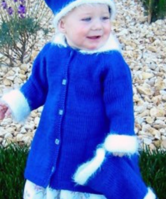A toddler in a knitted coat, hat, and muffler set.