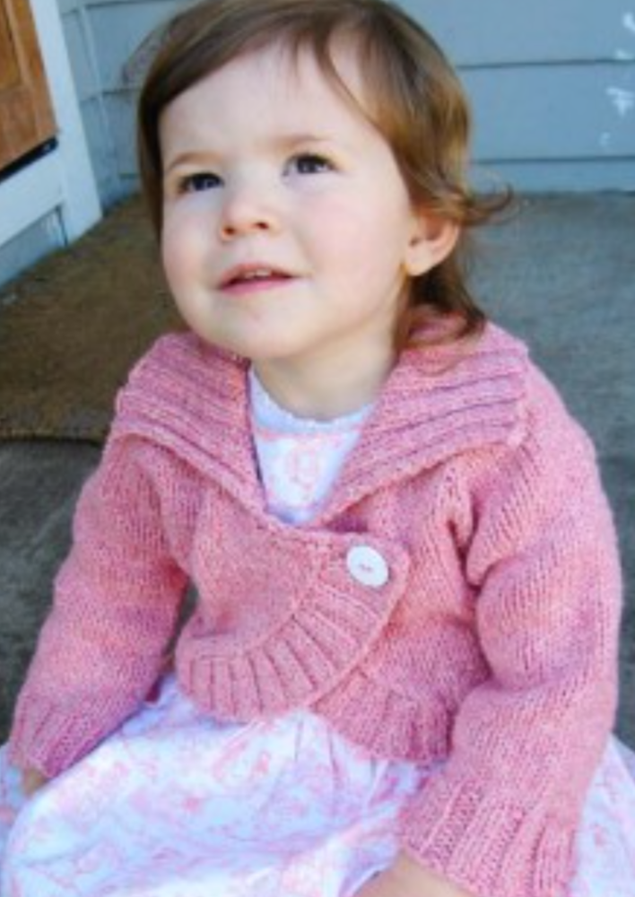 A female toddler wearing a knitted bolero sweater