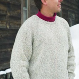 A man wearing a knitted sweater standing in the snow