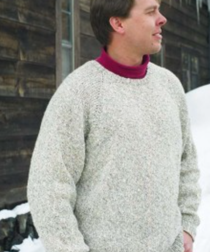 A man wearing a knitted sweater standing in the snow