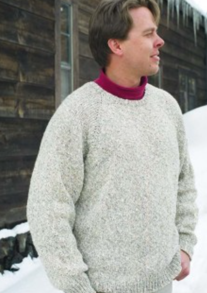 A man wearing a knitted sweater standing in the snow