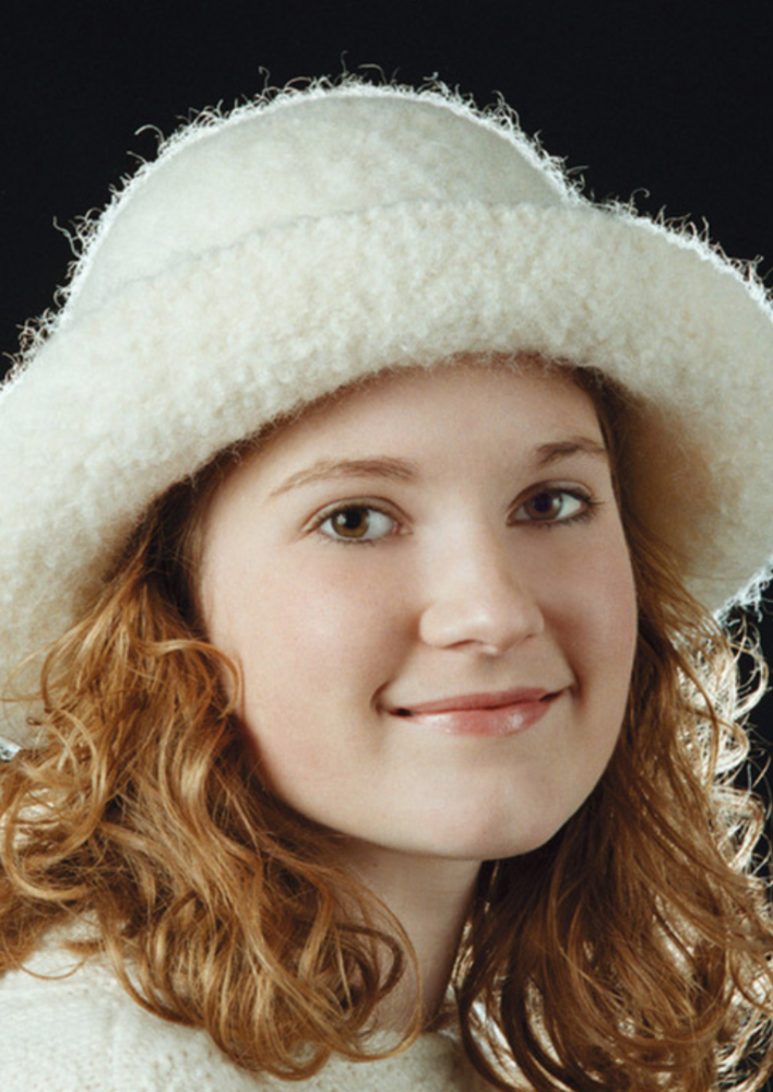 A girl wearing a white, felted hat with brim