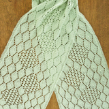 A lacy, knitted scarf on a wooden surface