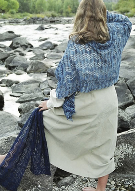 A woman wearing a knitted shawl and holding a scarf
