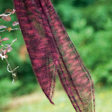 A beaded, knitted scarf hanging from a tree