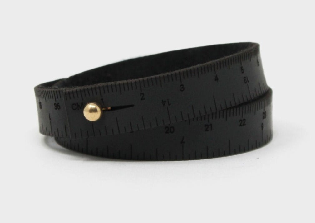 A photo of a black wrist ruler with engraved measurements