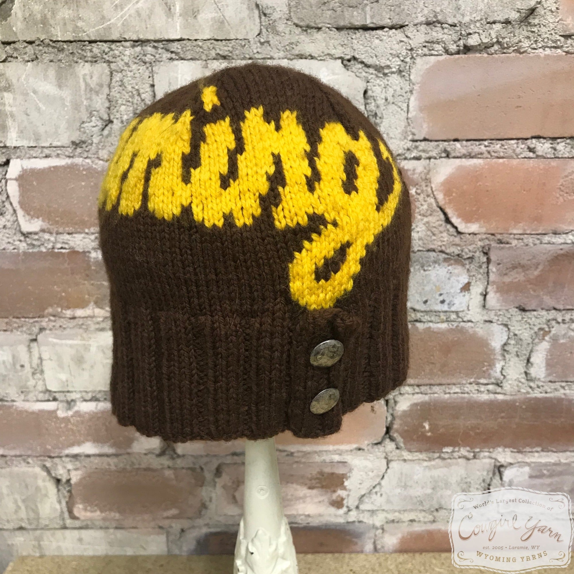A brown and gold beanie hat with buttons that says Wyoming 