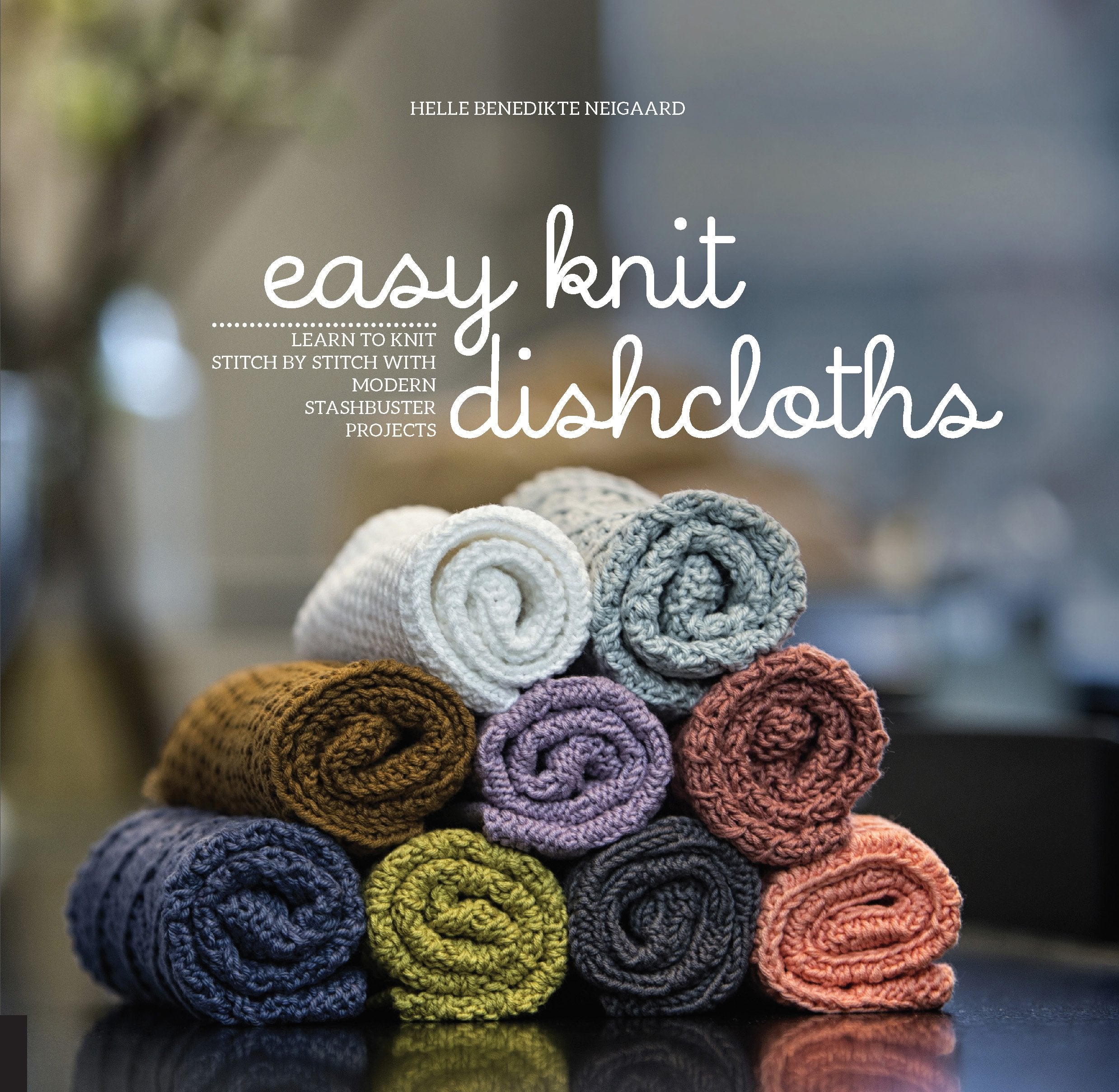 Author Helle Benedikte Neigaard. Easy knit dishcloths. Learn to knit stitch by stitch with modern stashbuster projects. Depicts a stack of dishcloths.