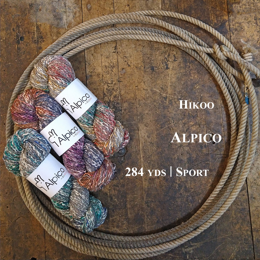Three colorful hanks of HiKoo Alpico yarn in a lasso on a wooden surface