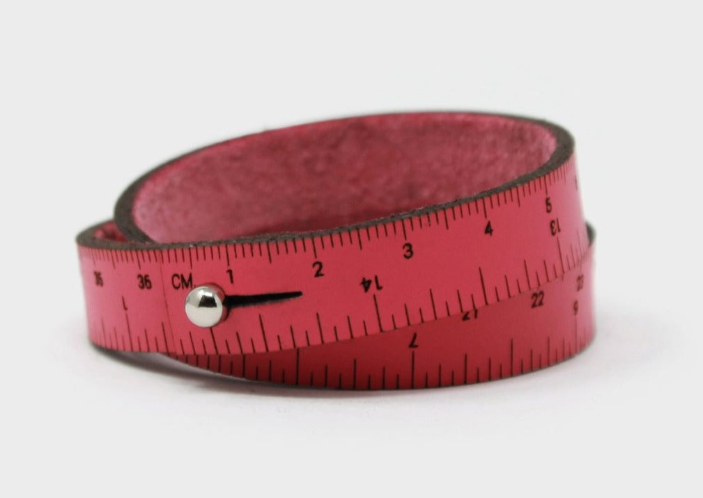 A photo of a pink wrist ruler with engraved measurements