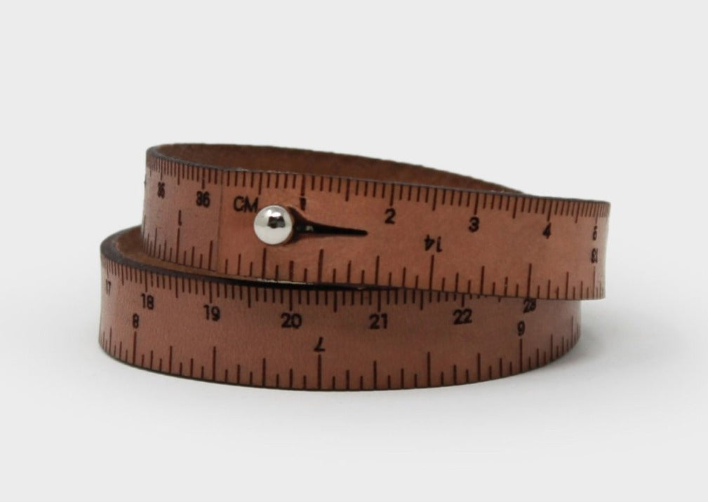 A photo of a medium brown wrist ruler with engraved measurements