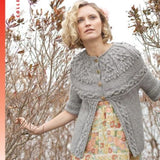 cover of norah gaughan vol 9, a woman in gray sweater peers through the brush