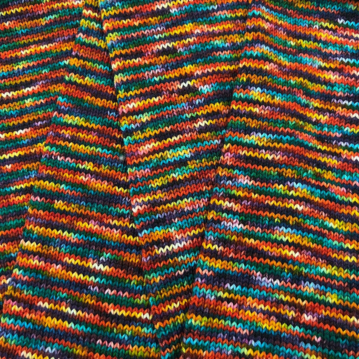 A rich, multi-colored skein of How We Show Up turned into a sock tube