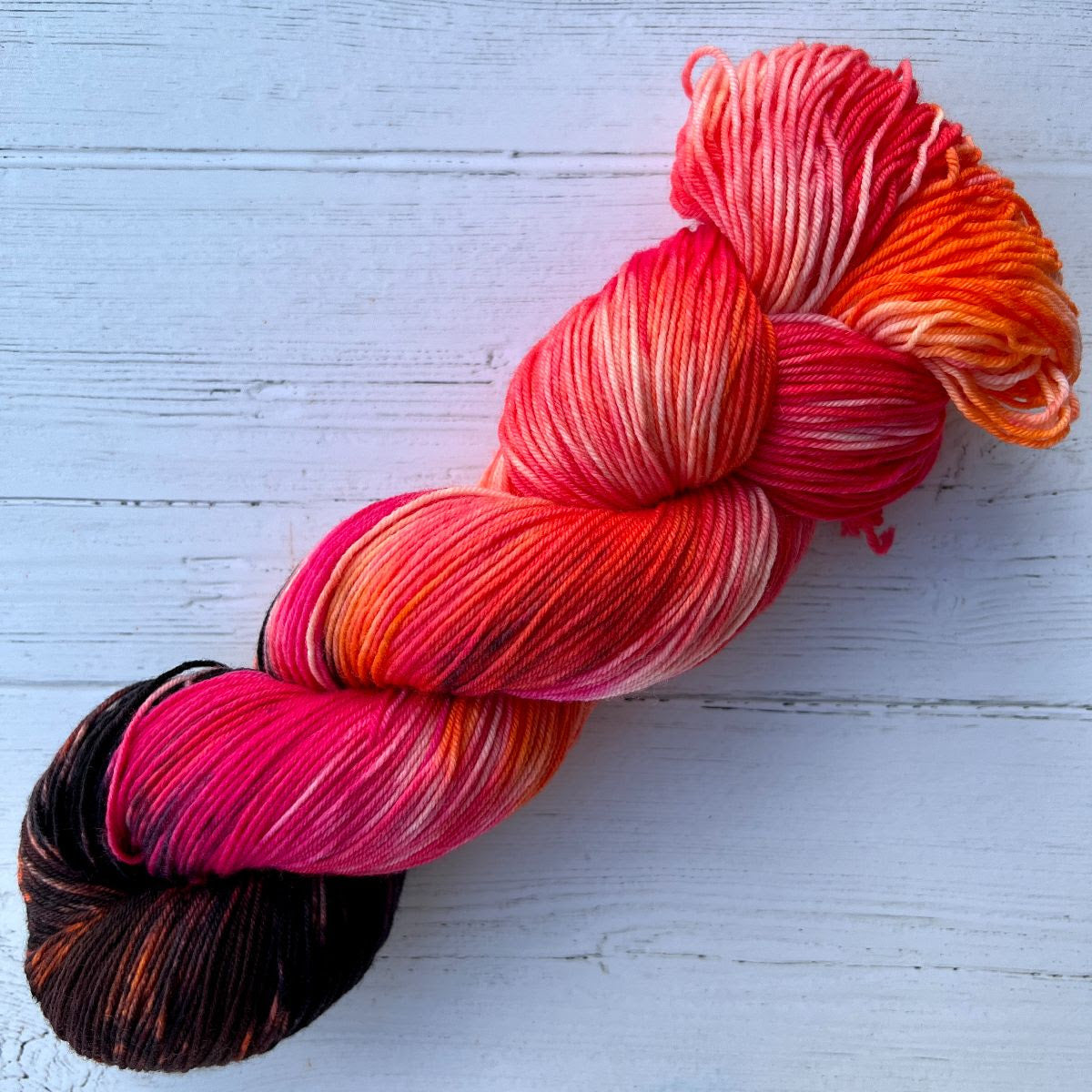 Feb 2023 Herstory: Lilith's Brood, a pink/black/orange skein twisted into a hank