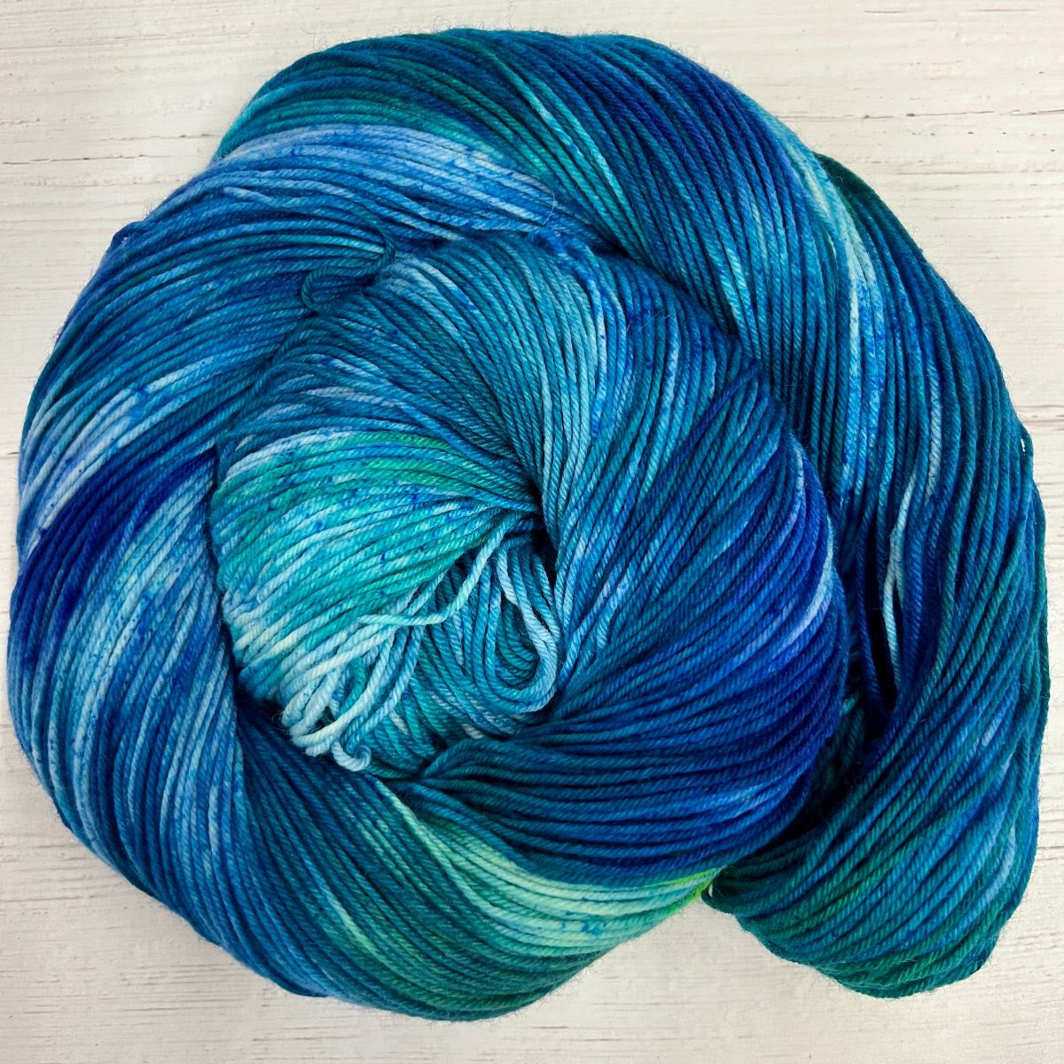 Knitted Wit Herstory 2022 color Burnout, a blue, teal, and green yarn, twisted into a spiral