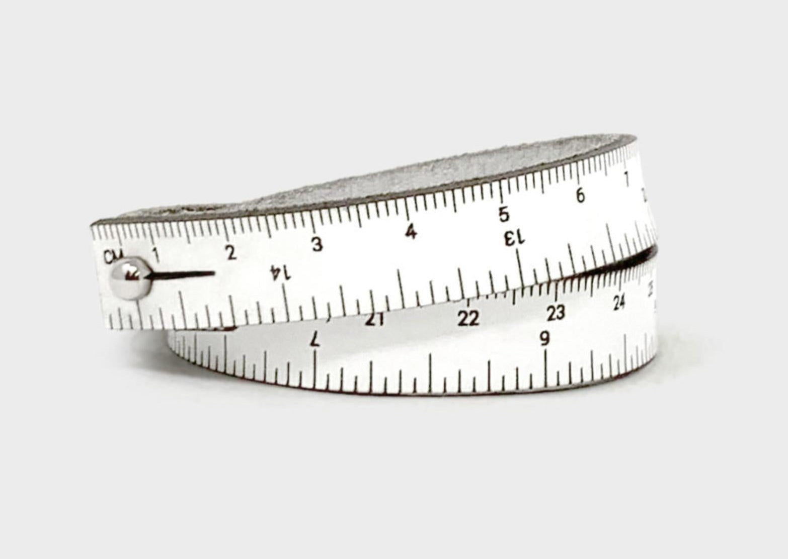 A photo of a white wrist ruler with engraved measurements